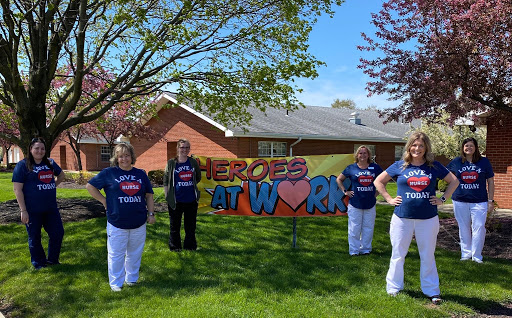 A group of individuals proudly displaying a sign that reads 'Heroes at Work', celebrating dedication and teamwork in a vibrant outdoor setting.