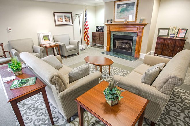 A cozy living room featuring sofas, a fireplace, and elegant decor with an American flag in the corner.