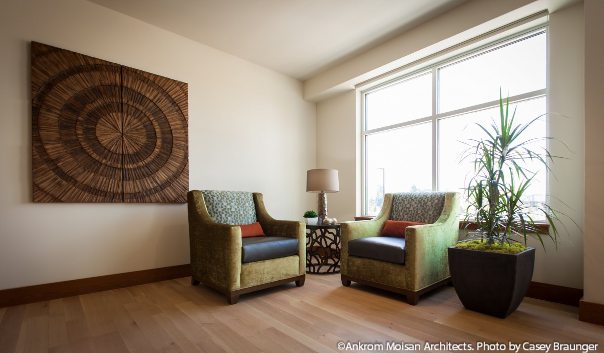 A cozy living room corner with two armchairs, a small table, and decorative elements by a large window.