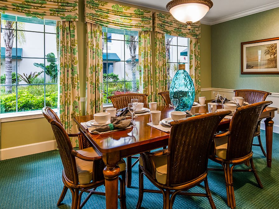 A elegantly set dining room table with chairs and colorful curtains in a well-decorated home.