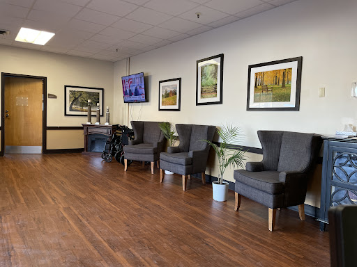 A cozy waiting area featuring comfortable chairs, decorative artwork, and a television.