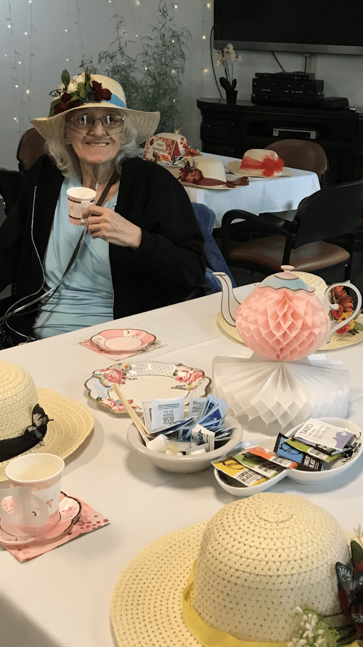 A person enjoys tea at a social gathering with decorative table settings.