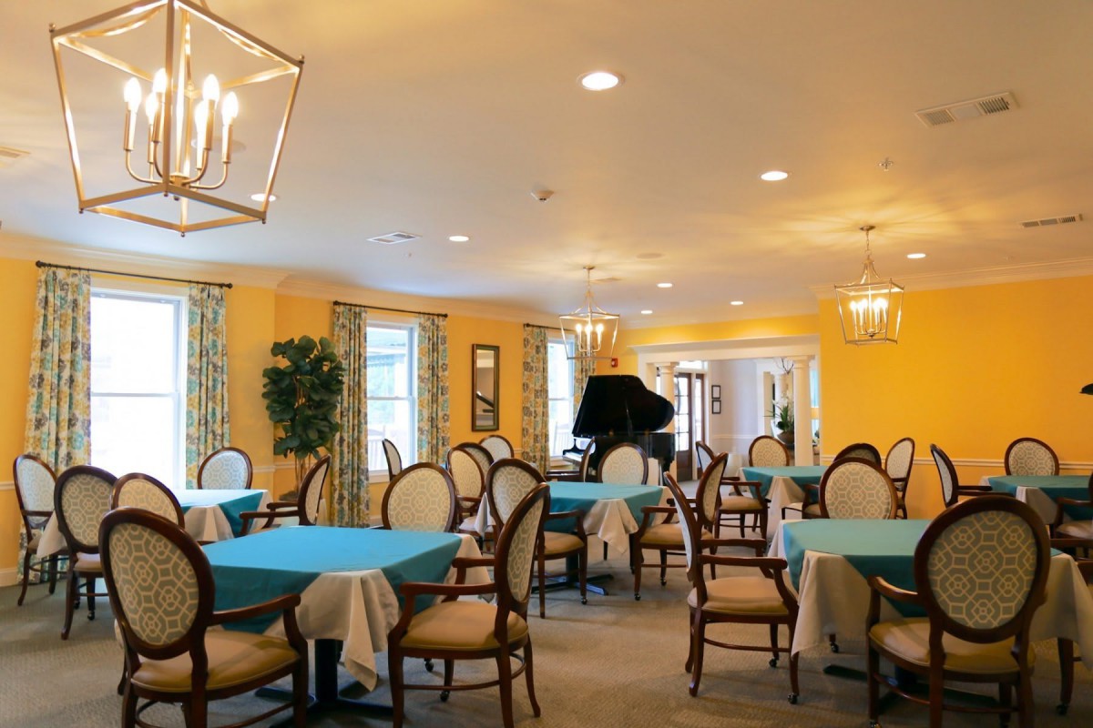 An elegant dining area with yellow walls, featuring tables set with turquoise tablecloths.