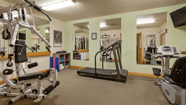 A small gym with exercise equipment, including a treadmill and weights.