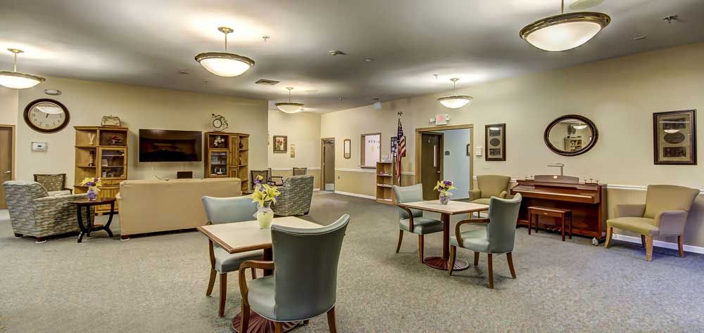 A spacious and well-lit lobby area with tables and chairs arranged for meetings or social gatherings.