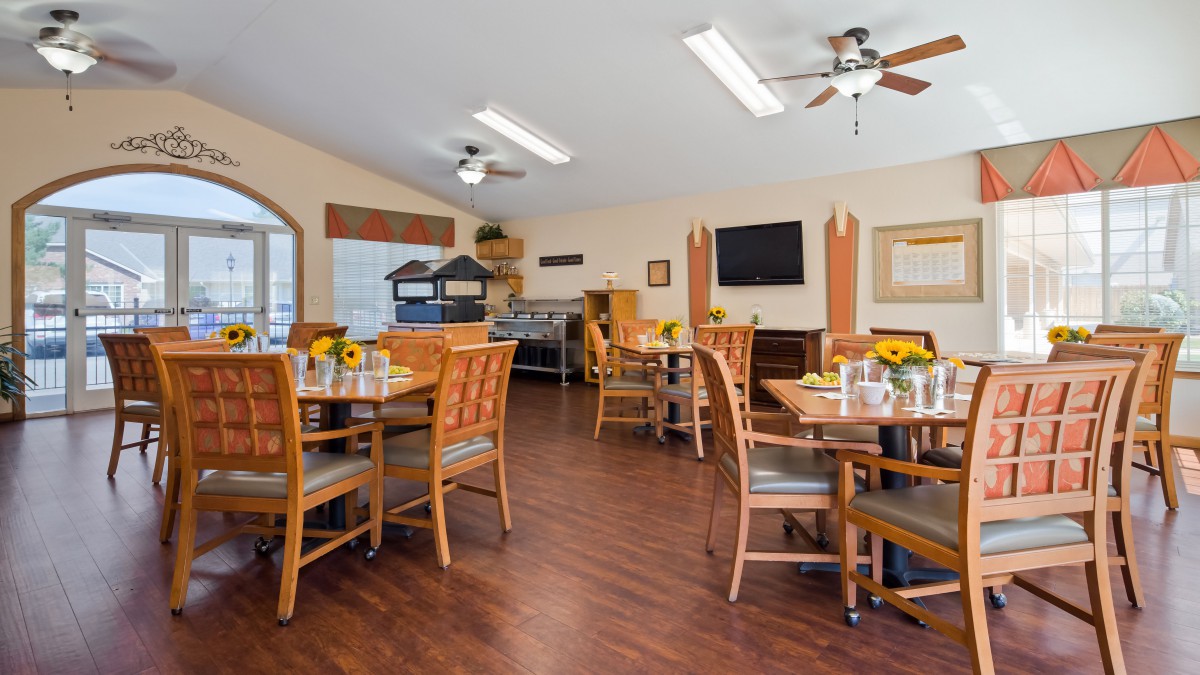 A cozy dining area with wooden floors, tables, chairs, and a television.