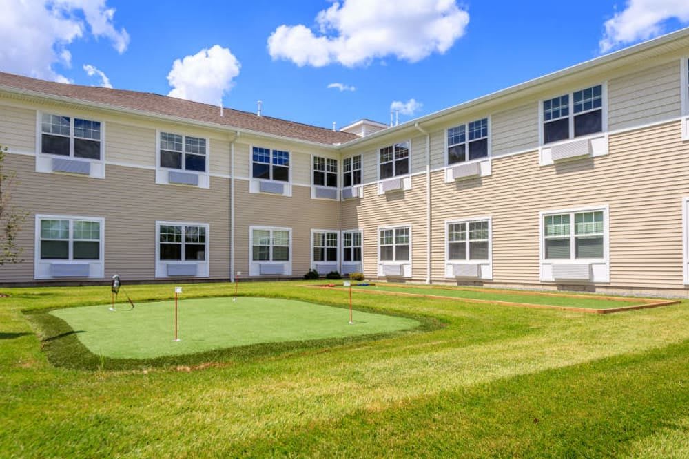 A building with a well-maintained lawn and golf green under a clear blue sky.