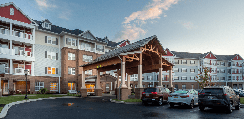 A modern hotel entrance with parked cars and a brick exterior.