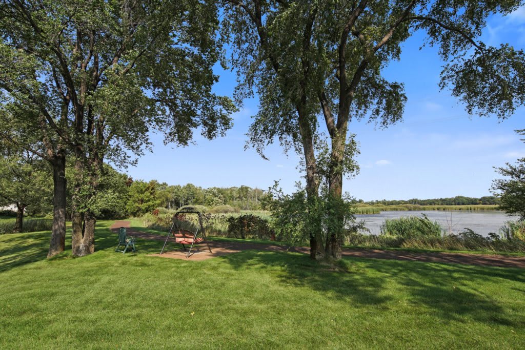 A peaceful park scene with a bench surrounded by trees, overlooking a lake.