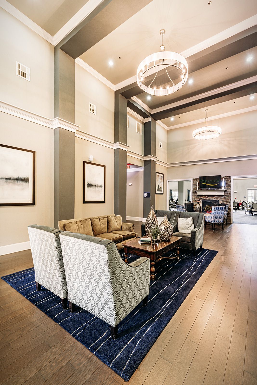 A spacious and elegantly designed living room with modern furniture, high ceilings, and a chandelier.