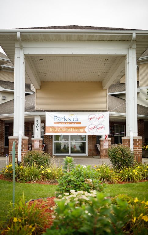 The entrance of a building featuring a banner and landscaped garden.