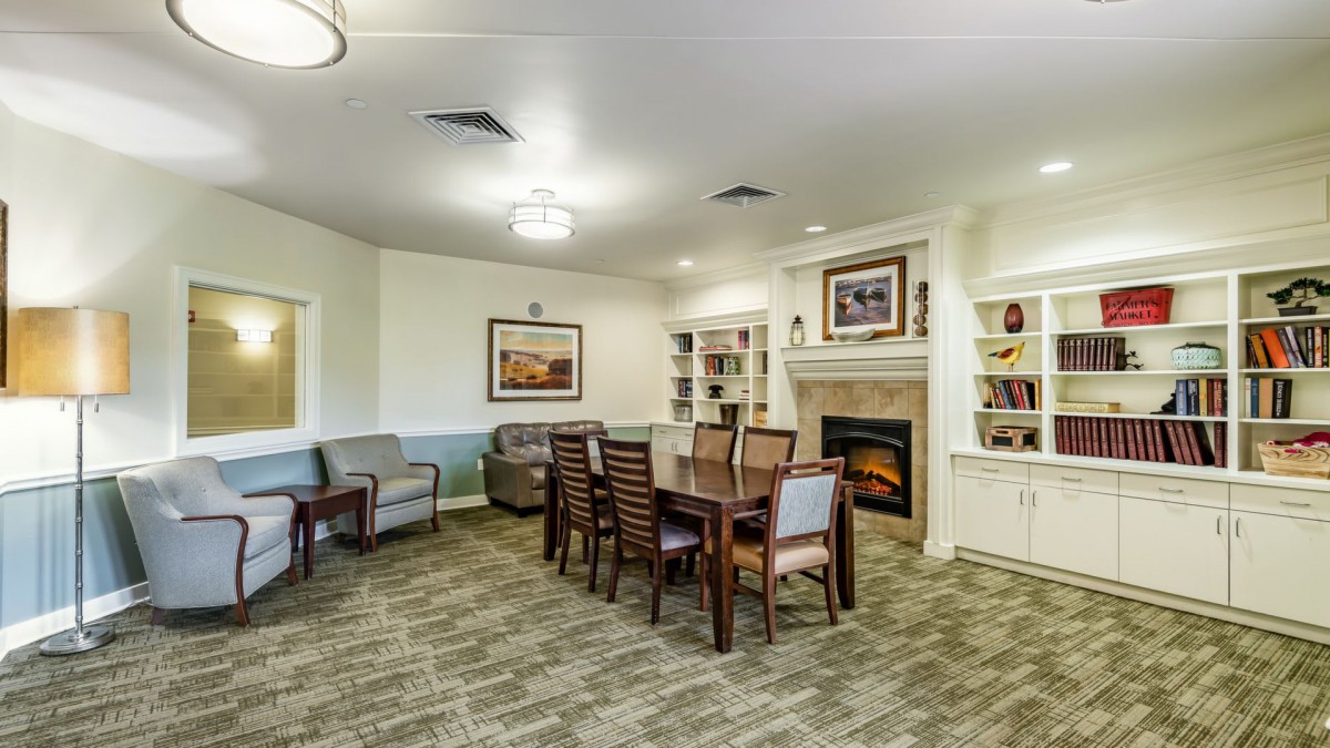 A cozy living and dining area featuring a fireplace, bookshelves, and ample seating.