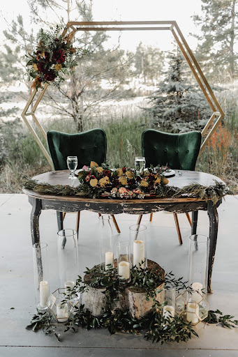 A beautifully decorated wedding table set for two, featuring elegant floral arrangements and candlelight amid a serene outdoor backdrop.