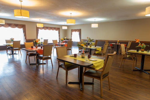 A spacious and inviting dining area with elegantly set tables and warm lighting.