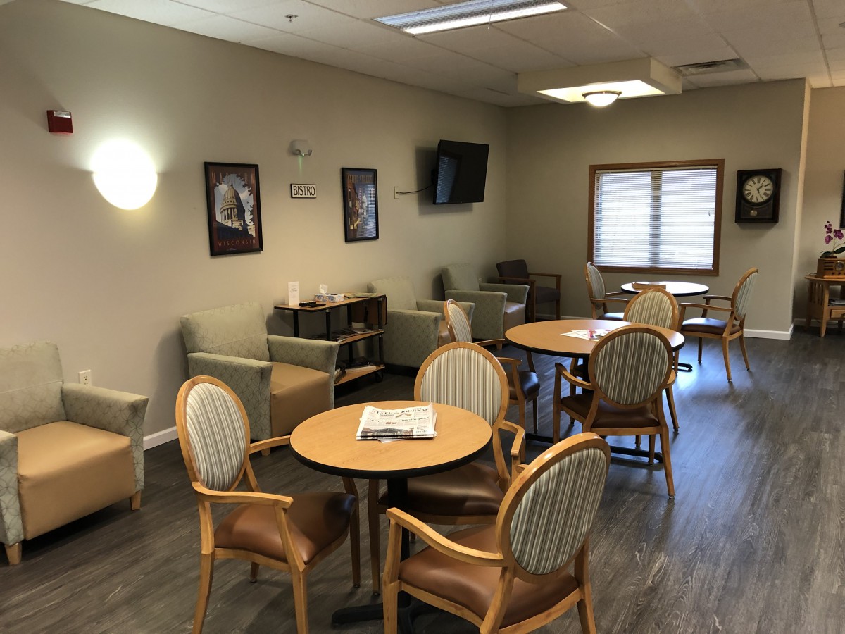 A waiting room with tables, chairs, and a television.