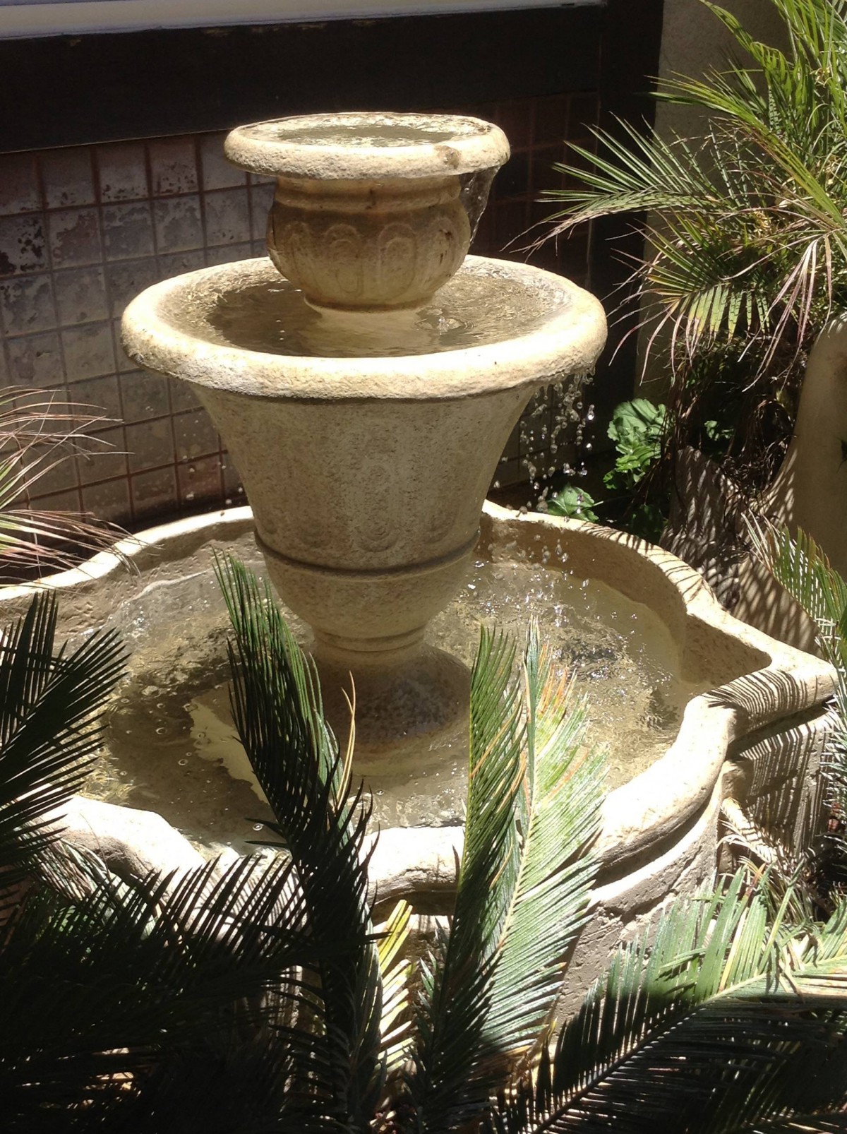 A decorative garden fountain surrounded by lush plants.