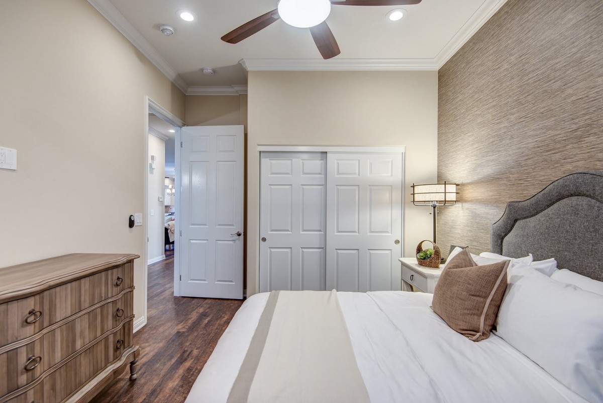 A cozy bedroom featuring a bed with pillows, a ceiling fan, and a closet with double doors.