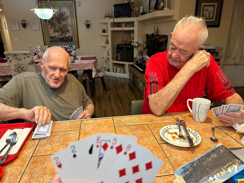 Two elderly men enjoying a card game at the dining table in a cozy kitchen setting.