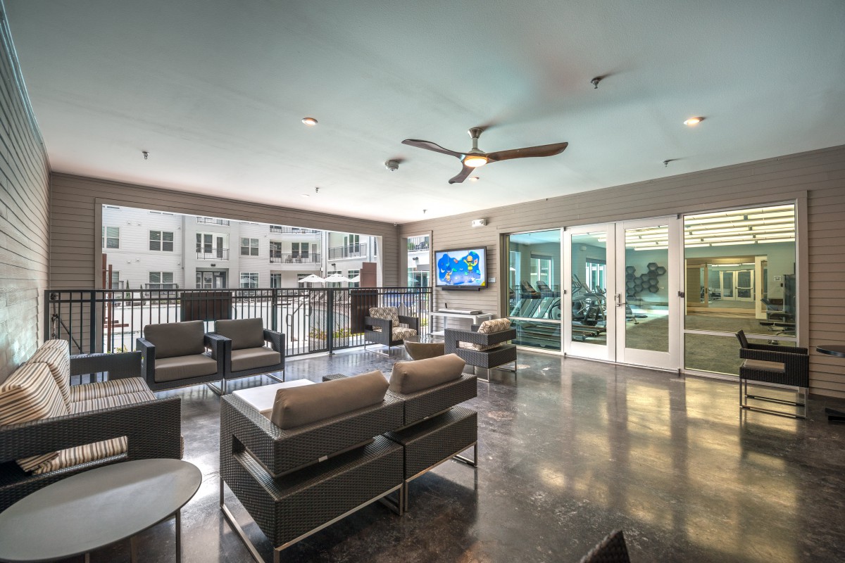 A modern lounge area with comfortable seating, a television, and large windows providing ample natural light.