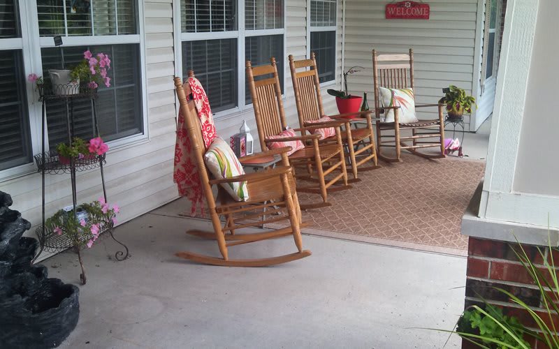 A cozy porch with several wooden rocking chairs and colorful cushions, perfect for relaxing.