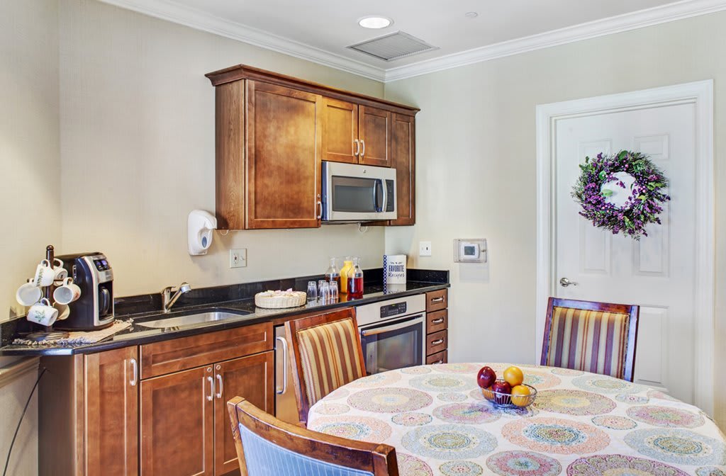 A cozy kitchen and dining area with a round table, chairs, wooden cabinets, and a microwave.