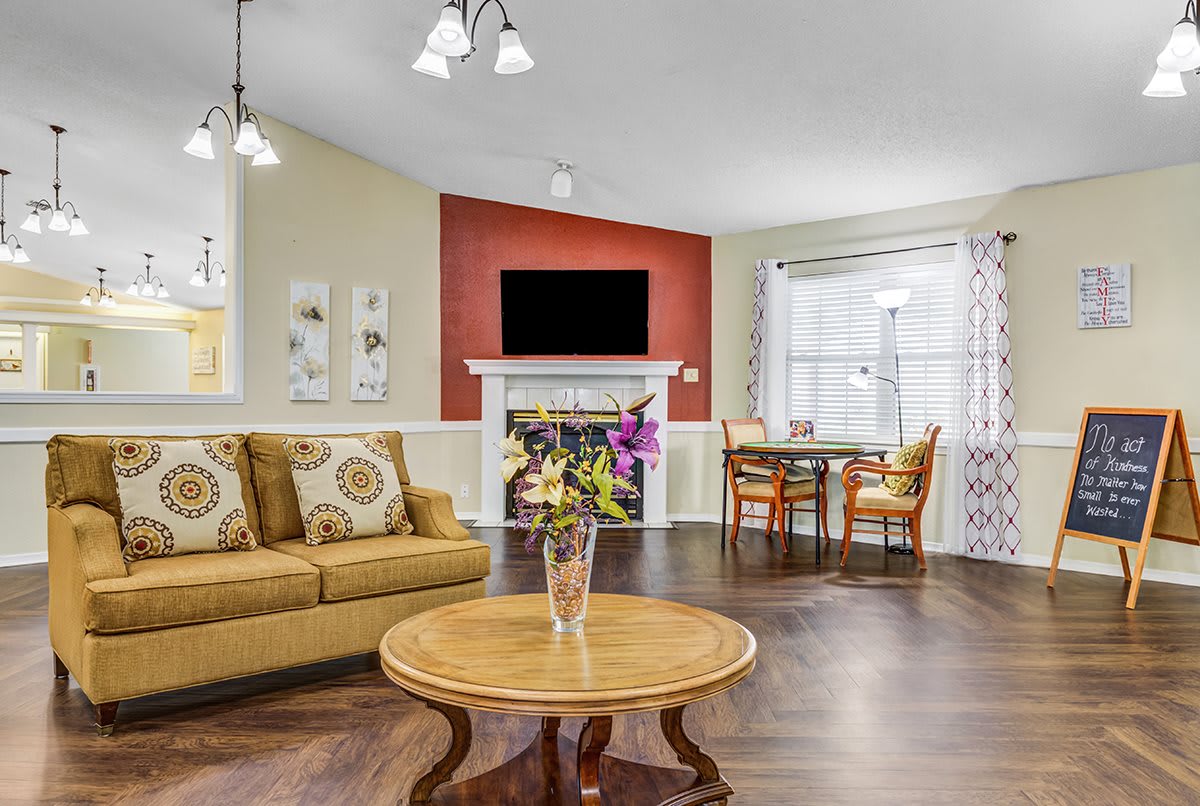 A cozy living room with a sofa, coffee table, and fireplace, featuring a connected dining area.