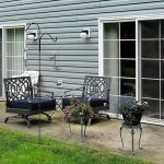 A cozy outdoor patio area with chairs, planters, and a sliding glass door leading to the interior.