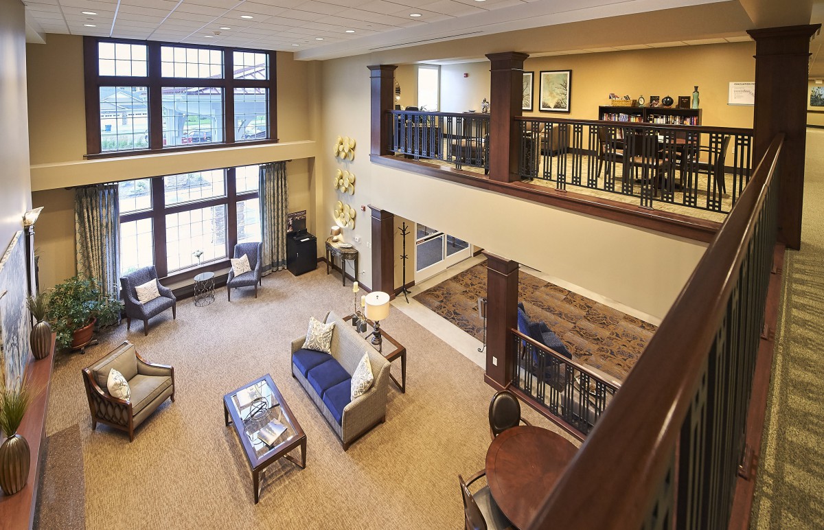 A spacious living room with a loft, featuring large windows and comfortable furniture.