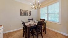 A cozy dining room with a table set for four under an elegant chandelier.