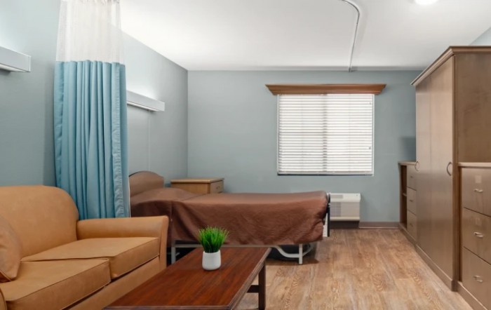 A minimalistic hospital room with a bed, sofa, and window.