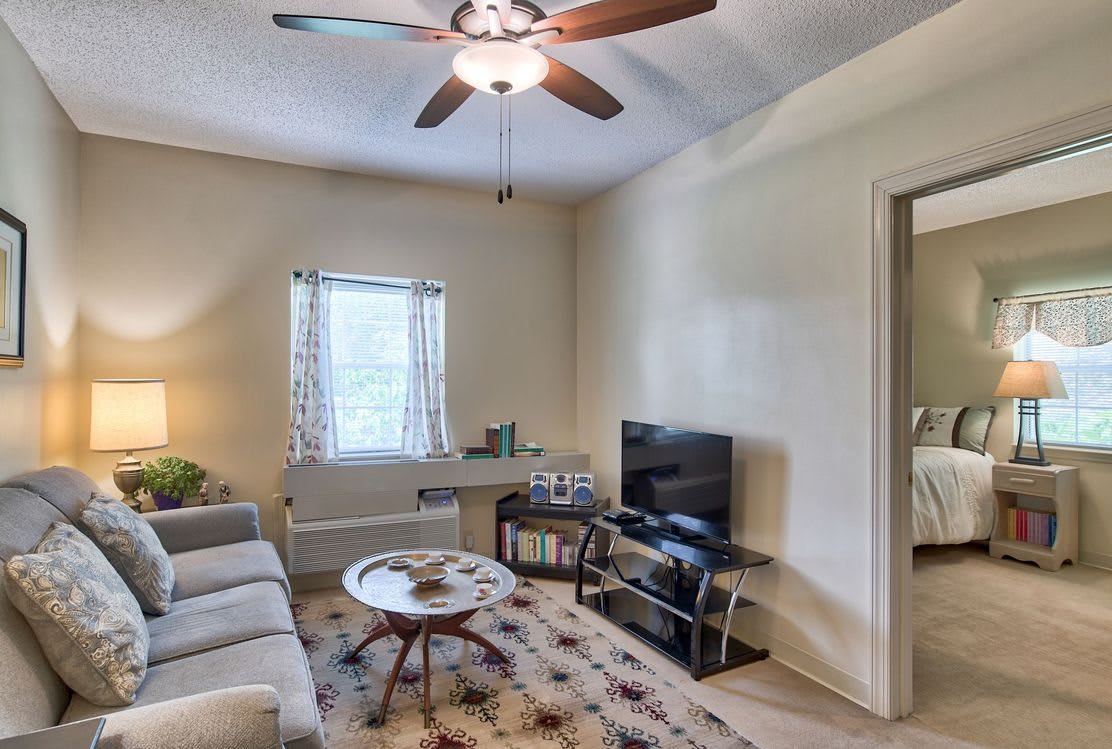 A cozy living room with a sofa, television, and coffee table under a ceiling fan.