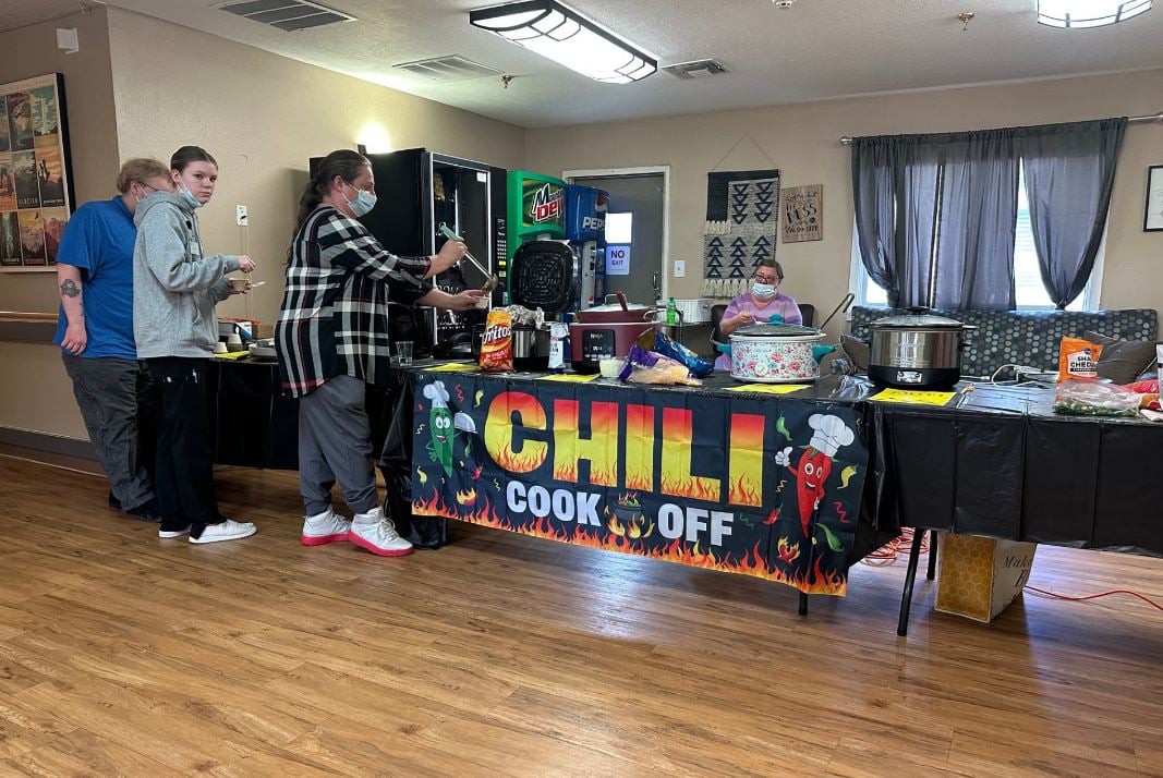 Participants setting up for a chili cook-off event in an indoor venue.