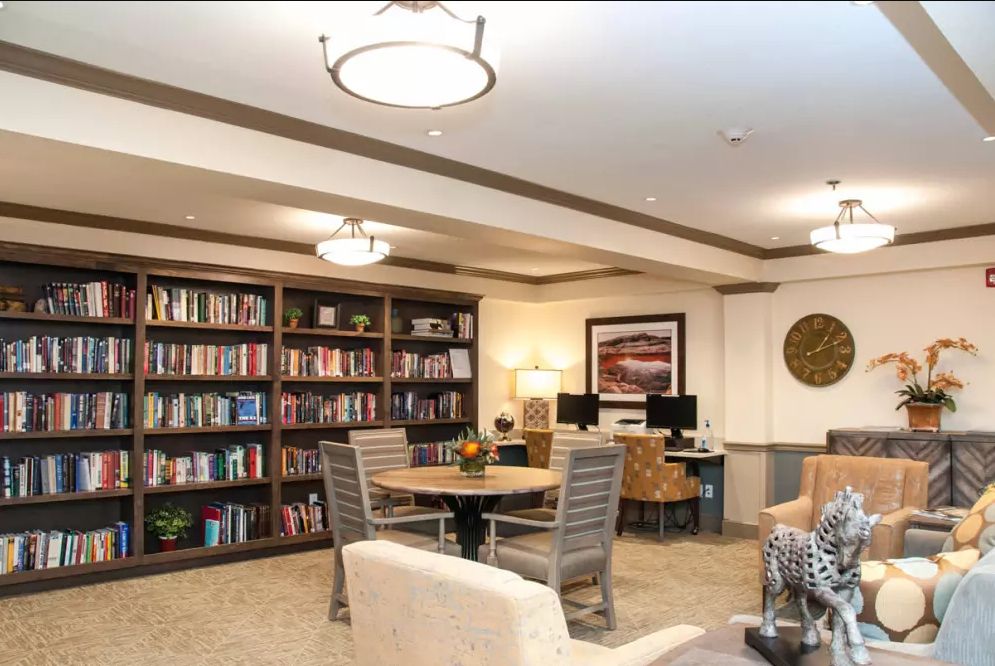 A cozy library space with bookshelves, seating, and computers for reading and study.