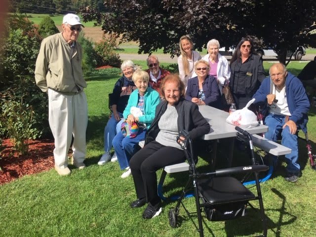 A group of seniors enjoying a sunny day at the park, gathered around a picnic table.