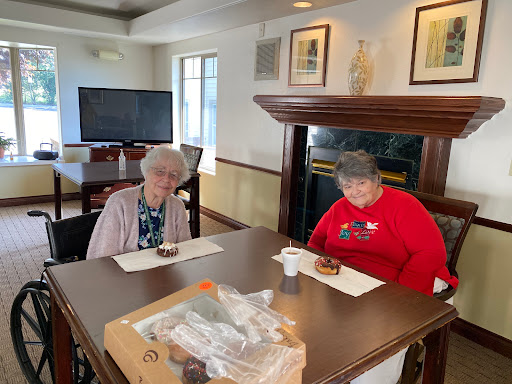Two elderly women enjoying dessert together in a cozy indoor setting.