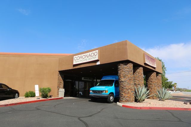 A commercial building with a van parked in front under a sunny blue sky.