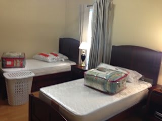 A tidy bedroom with two twin beds, featuring a bedside lamp and curtains.