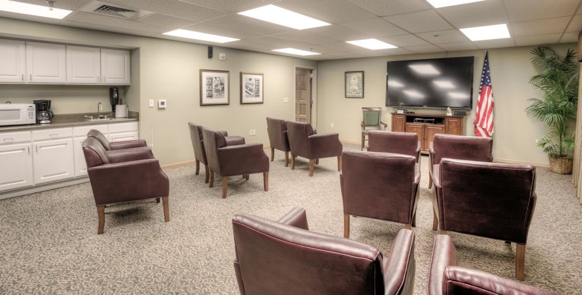 A small conference room with chairs arranged facing a large TV screen.
