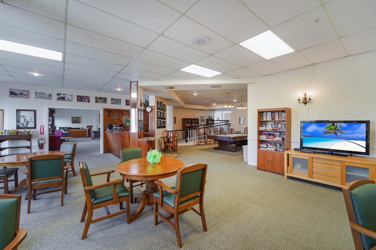 A cozy library interior with a reading area, bookshelves, and a table with chairs.
