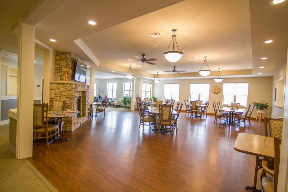A spacious and well-lit dining room with wooden floors and elegant furniture.