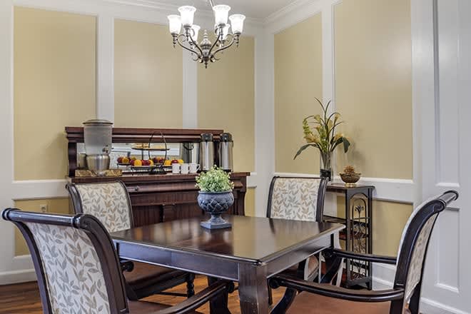 Elegant dining room with a wooden table, upholstered chairs, and a chandelier.