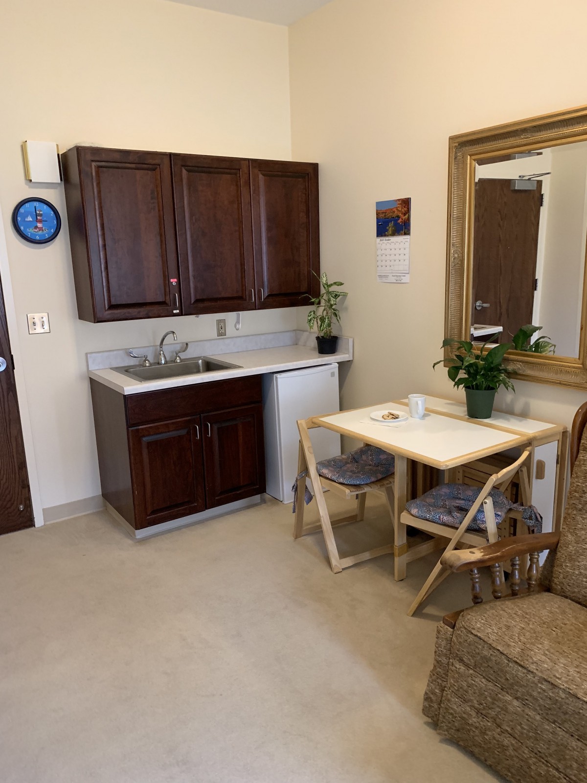 A cozy kitchenette featuring dark wood cabinets, a small table with chairs, and decorative plants.