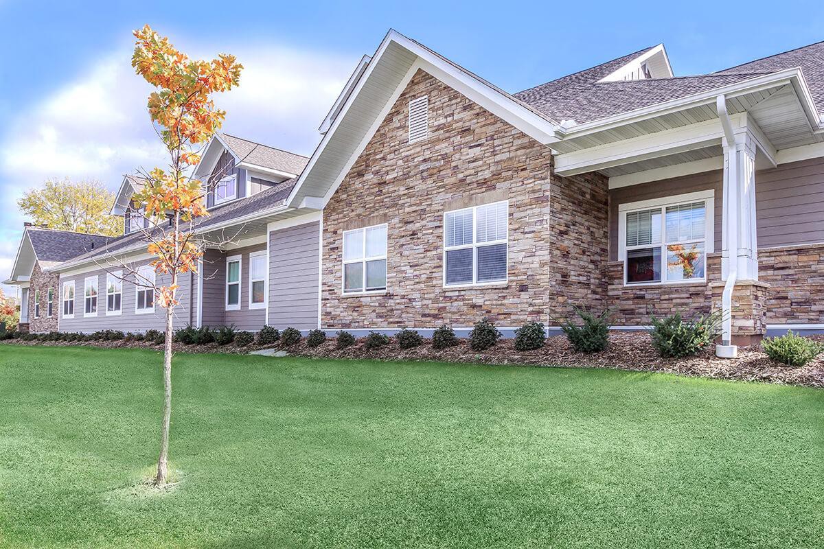 A suburban house with a brick and siding exterior and a well-maintained lawn.