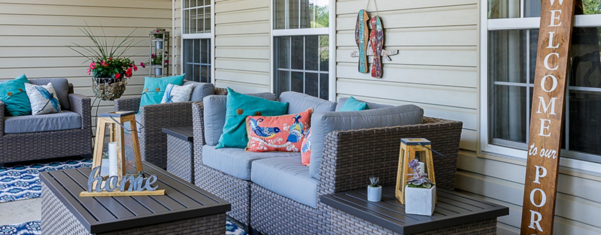 A cozy patio setting with rattan outdoor furniture featuring colorful cushions and decorative wall art.