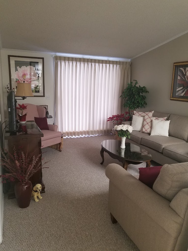 A cozy living room with neutral tones, featuring a sofa, coffee table, and artwork on the walls.