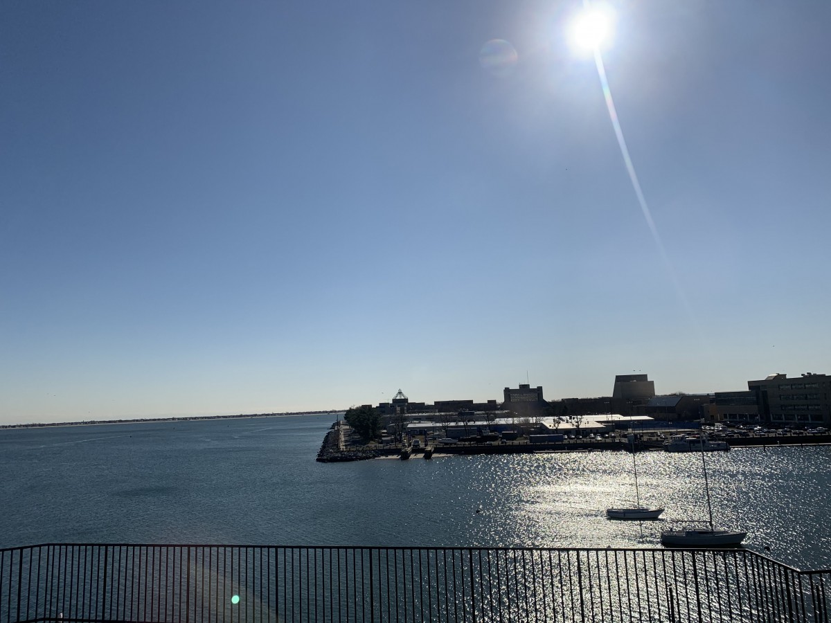 A sunny day overlooking a harbor with boats and buildings along the coastline.