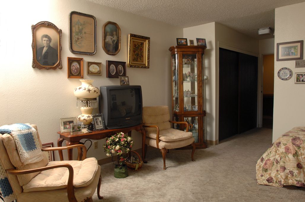 A cozy living room with vintage decor and antique furniture, featuring a classic TV and framed wall art.