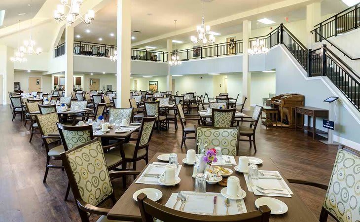 A spacious dining area with neatly arranged tables and chairs, elegantly decorated with warm lighting.
