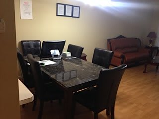 A home office setup on a dining table with a sofa in the background.