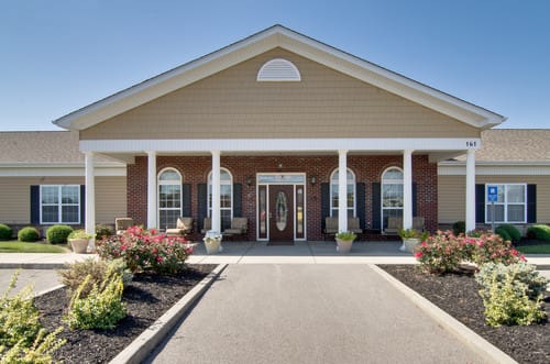 A welcoming entrance to a residential building with landscaped surroundings and classic column architecture.